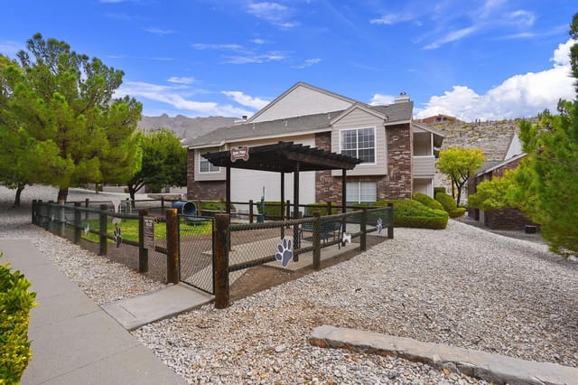 Exterior view of a multifamily building with a fenced dog park and gravel landscaping.