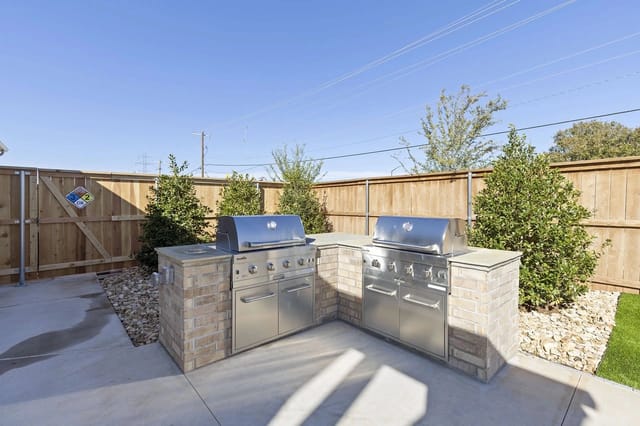 Outdoor kitchen area with two stainless steel grills built into a brick counter with stone accents.