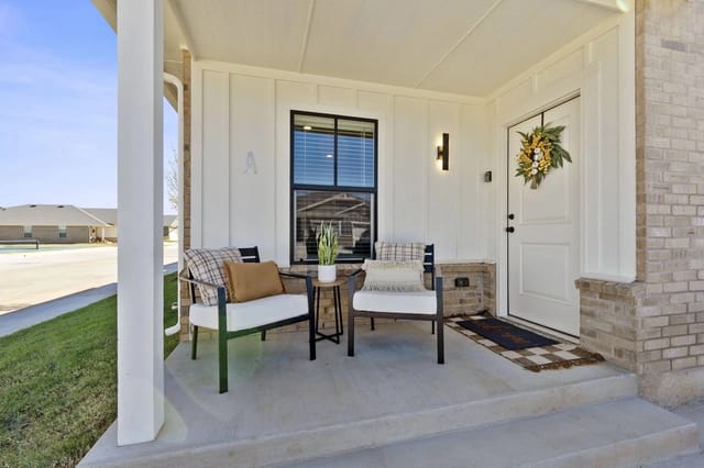 Porch with two chairs and a small table in front of a white door with a wreath.