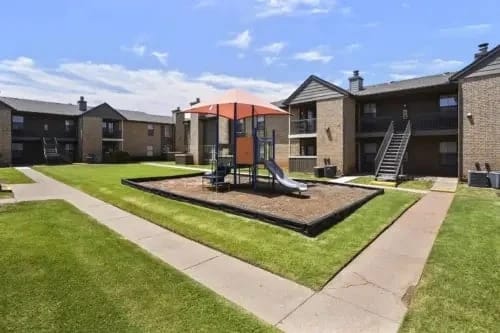 Playground area with slides and swings in the courtyard of an apartment building.