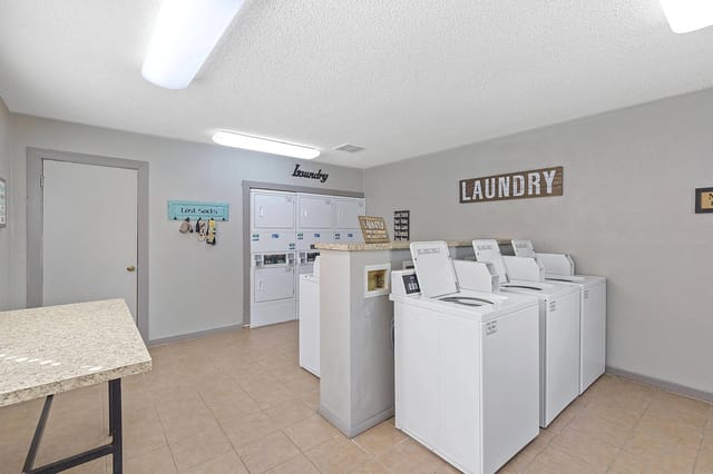 A laundry room with a row of washers and dryers.