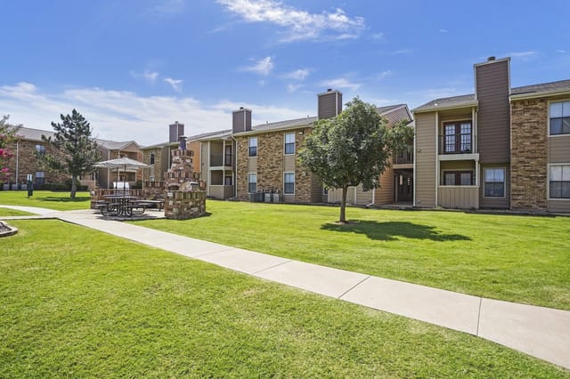 Apartment building exterior with picnic area and outdoor grill.