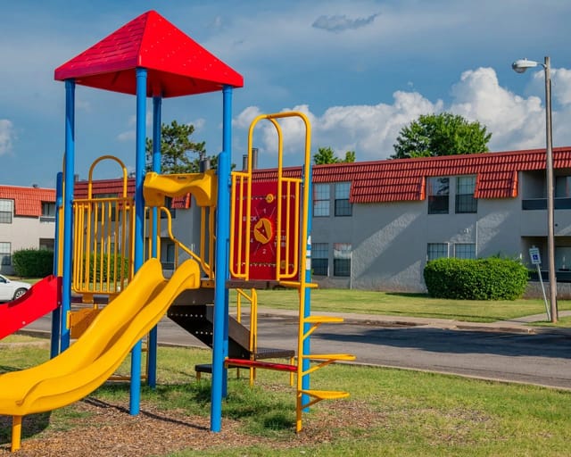 Playground with slides and swings in front of apartment buildings.