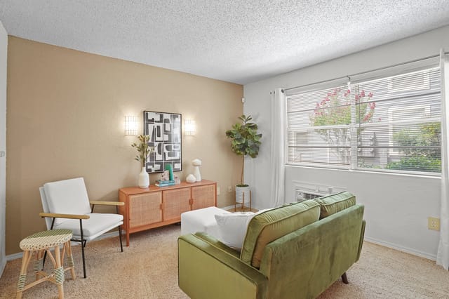Modern living room with green sofa, white armchair, and wood console.