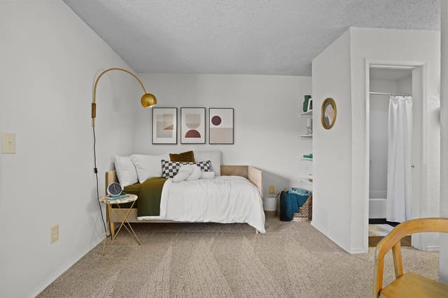 A stylish bedroom with a daybed, modern lamp, and artwork.