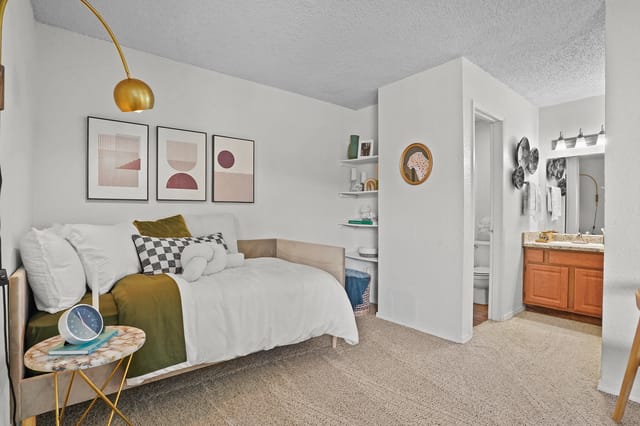 Stylish bedroom with a daybed, abstract art, and a glimpse of the bathroom vanity.