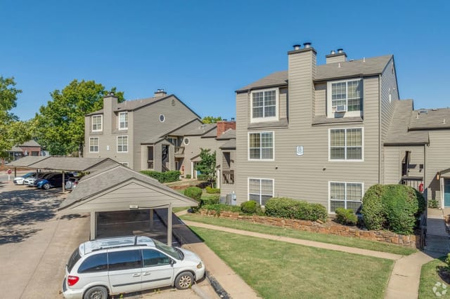 Exterior view of apartment buildings with covered parking and landscaping.
