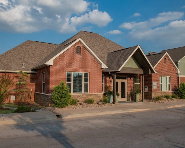 Exterior view of a brick apartment community building with front entrance and landscaping.