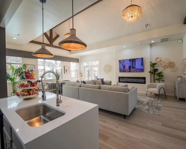 Open-concept community lounge with a large sectional, TV, fireplace, and kitchen island.