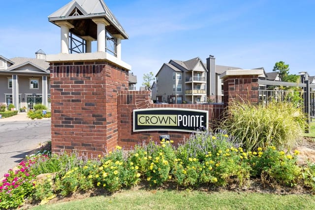 Crown Pointe apartment community entrance monument sign with brick pillar and landscaping.