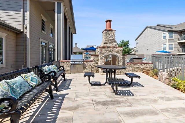 Outdoor seating area with a built-in grill and stone fireplace.