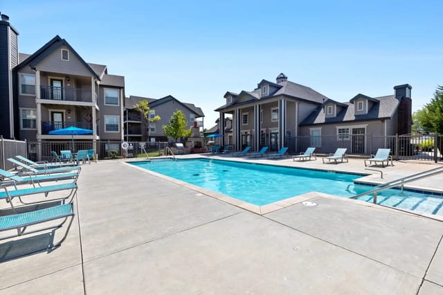 Resort-style swimming pool with lounge chairs and apartment buildings in the background.