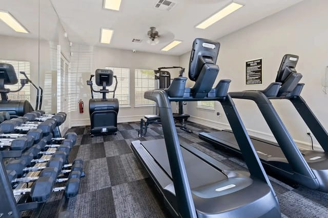 Fitness center with treadmills, elliptical machines, and free weights.