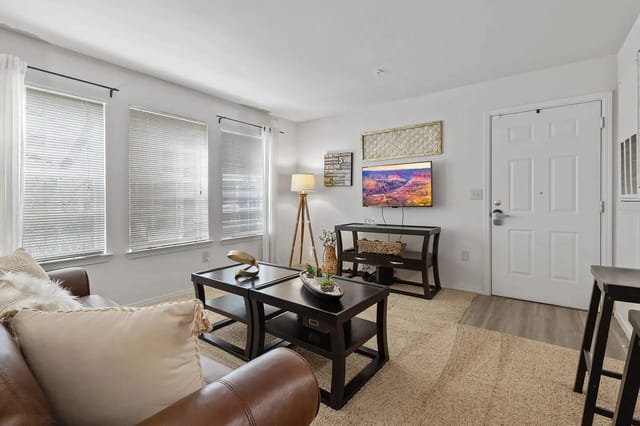 Living room with brown leather sofa, coffee tables, and a mounted TV.