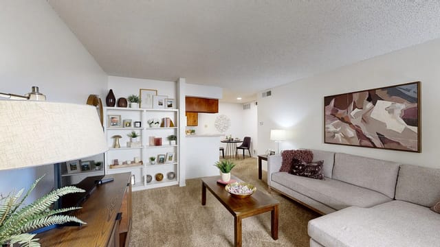 Living room with sectional sofa, coffee table, and bookshelf.