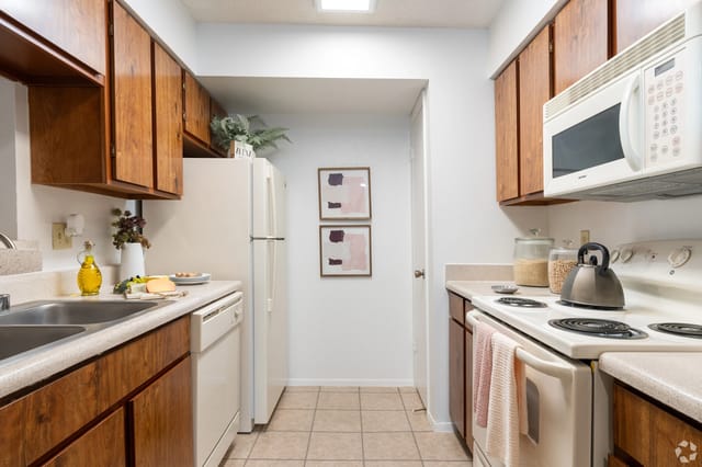 Kitchen with wood cabinets, white appliances, and a sink.