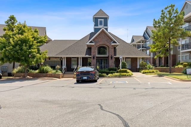 Exterior view of an apartment community entrance with parking and landscaping.