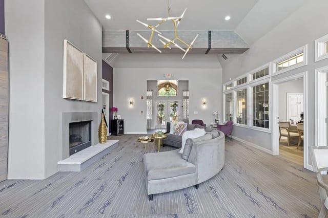 Bright lobby with gray sectional sofa, fireplace, and modern chandelier.