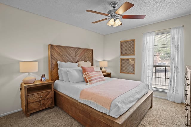Bedroom with a wooden bed frame, white linens, and coral accents.