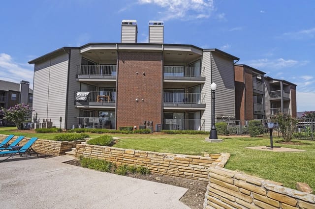 Exterior view of the apartment buildings with balconies and a stone retaining wall.