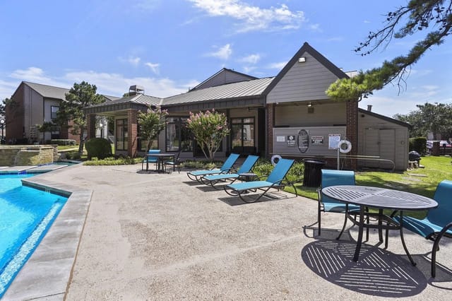 Outdoor swimming pool with lounge chairs and a table.