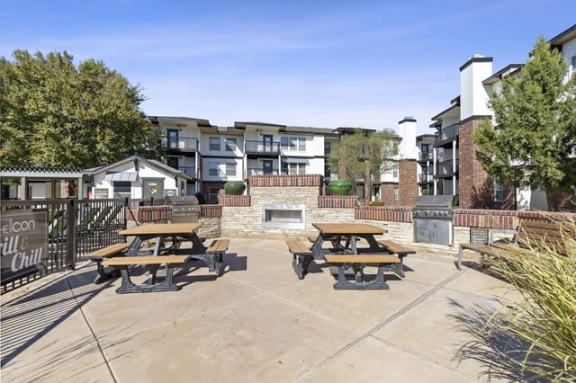 Outdoor community courtyard with brick planters, grills, and wooden picnic tables.