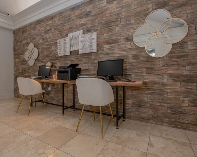 Leasing office workstation with two computers, printer, and stone accent wall.