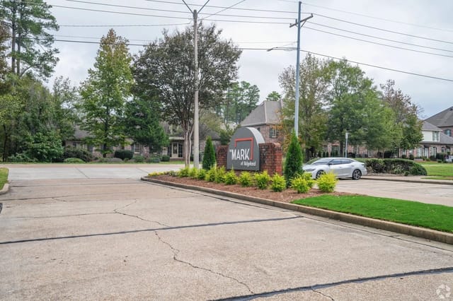 Entrance sign for The Mark of Ridgeland apartment community with landscaping and a car nearby