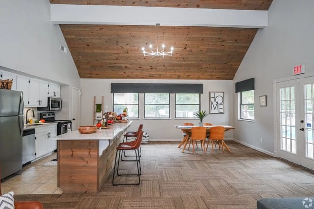 Open communal kitchen and dining area with a wood vaulted ceiling and large windows.