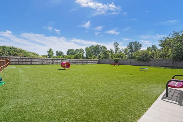 Open grassy community lawn with a small playground and surrounding wooden fence.