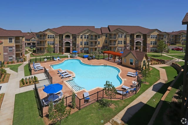 Outdoor pool area with lounge chairs and surrounding apartment buildings.
