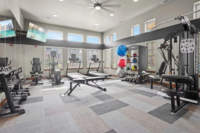 Bright community gym with treadmills, weights, and a rack of exercise balls.