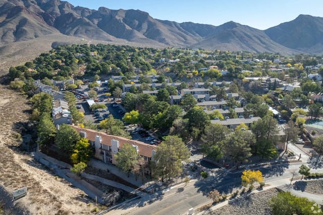Aerial view of apartment buildings nestled in a hillside with mountains in the background.