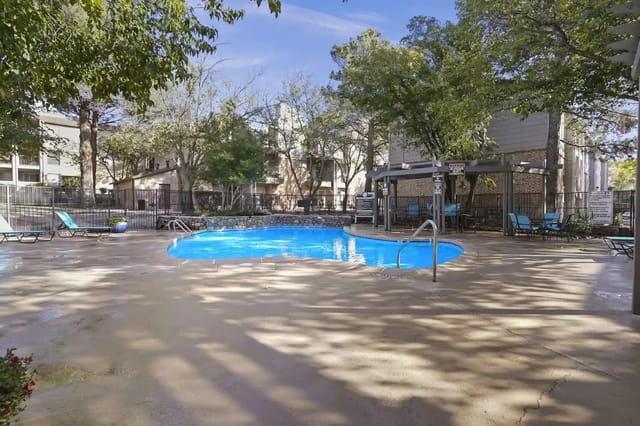 Outdoor swimming pool with lounge chairs and shaded seating areas.