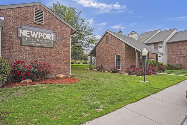 Exterior view of Newport leasing office sign on brick building with landscaped lawn.