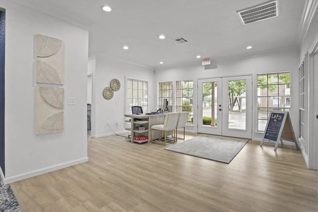 Bright apartment community lobby with reception desk, seating, and glass doors.
