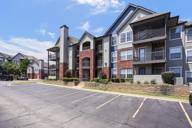 Exterior view of apartment buildings with parking lot in foreground.