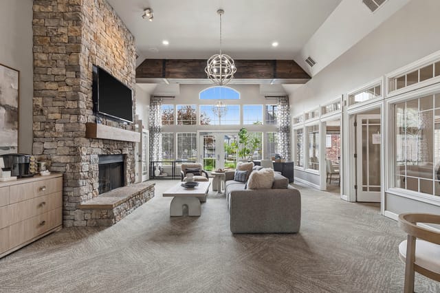 Spacious community lounge with a stone fireplace, comfortable seating, and large windows.