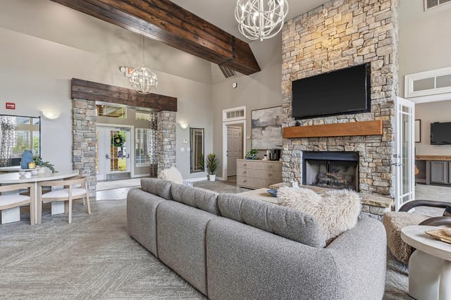 Stylish communal living room with a stone fireplace, comfortable seating, and decorative elements.
