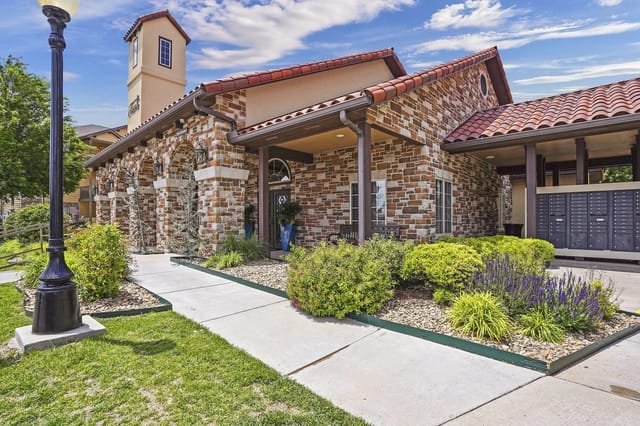 Building exterior with stone accents, covered walkway, mailboxes, and landscaping.