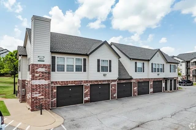 Exterior of a multi-family apartment complex with row of townhome-style buildings and attached garages.
