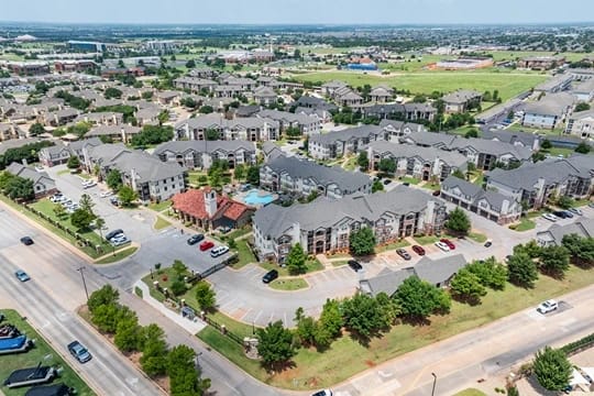 Aerial view of a large multifamily apartment community with many buildings, parking lots, and green spaces.