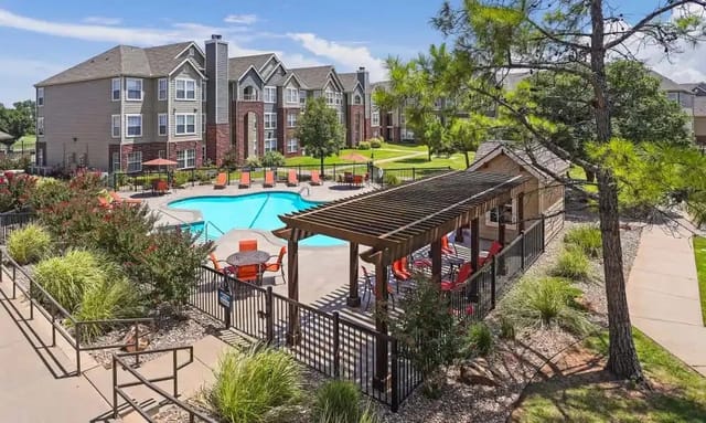 Outdoor pool area with seating and a shaded pergola at a multifamily community.