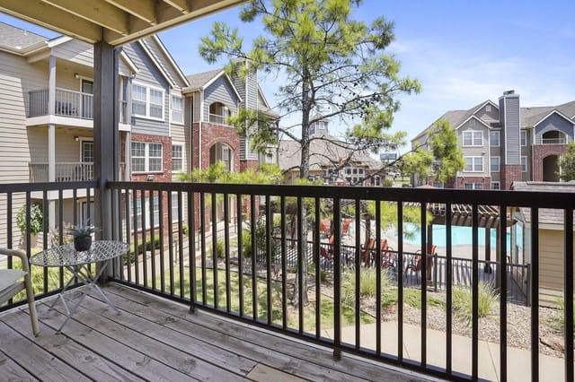 View from a balcony overlooking a communal pool area and apartment buildings.