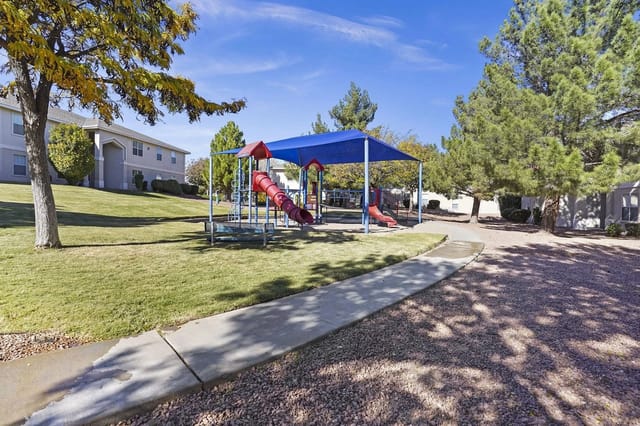Playground area with slides and climbing structures under a blue canopy.