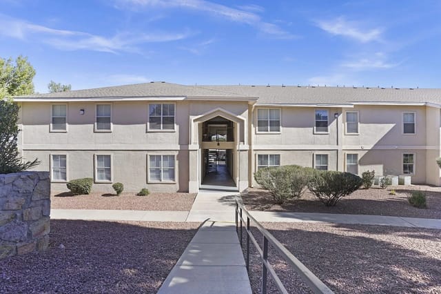Exterior view of a two-story apartment building with a central walkway leading to the entrance.