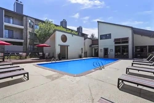 Outdoor pool at an apartment community with lounge chairs around.