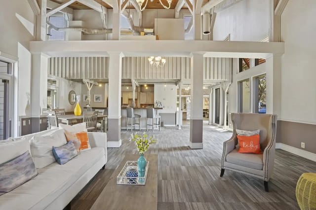 Open-concept community lounge with sofa, armchair, dining area, and visible kitchen.