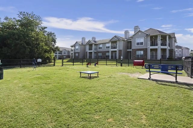 Open grassy community courtyard with playground equipment and apartment buildings in the background.