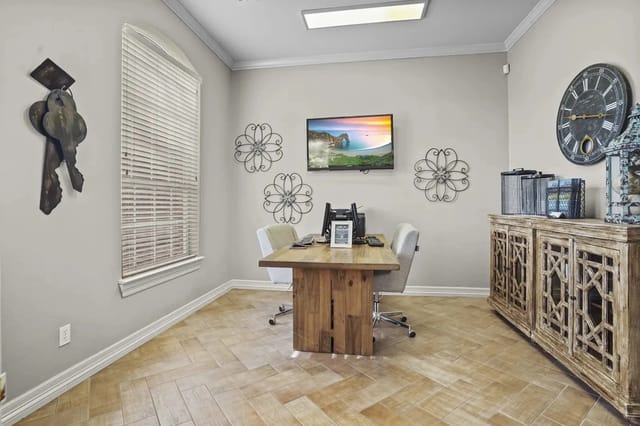 Leasing office in a community room with a wooden table, four chairs, wall art, and a mounted TV.